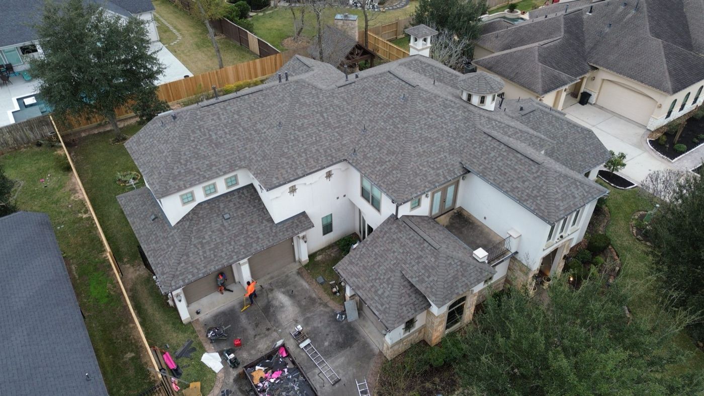 Aerial view of a full roof tear-off and replacement in progress on a large home