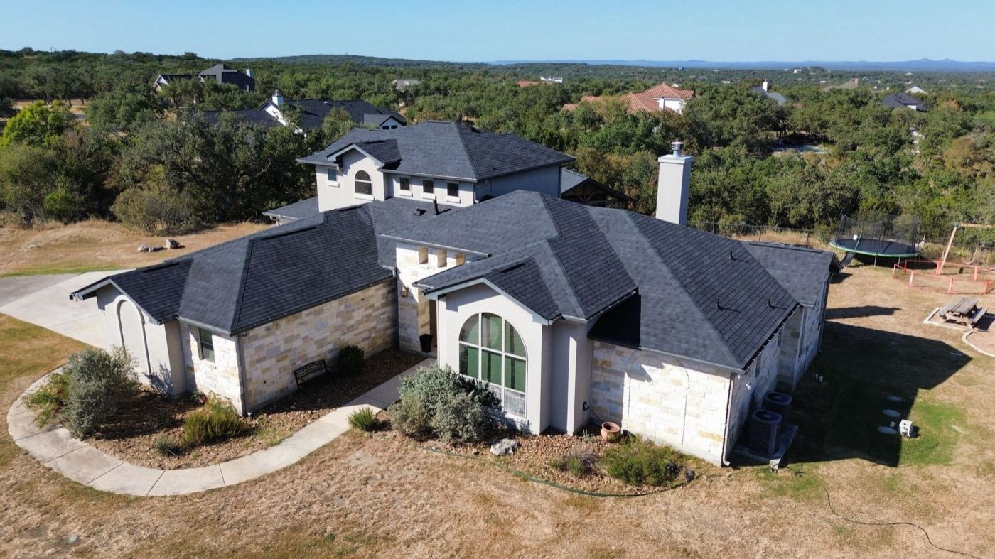 Aerial view of a completed roof replacement on a luxury stone home