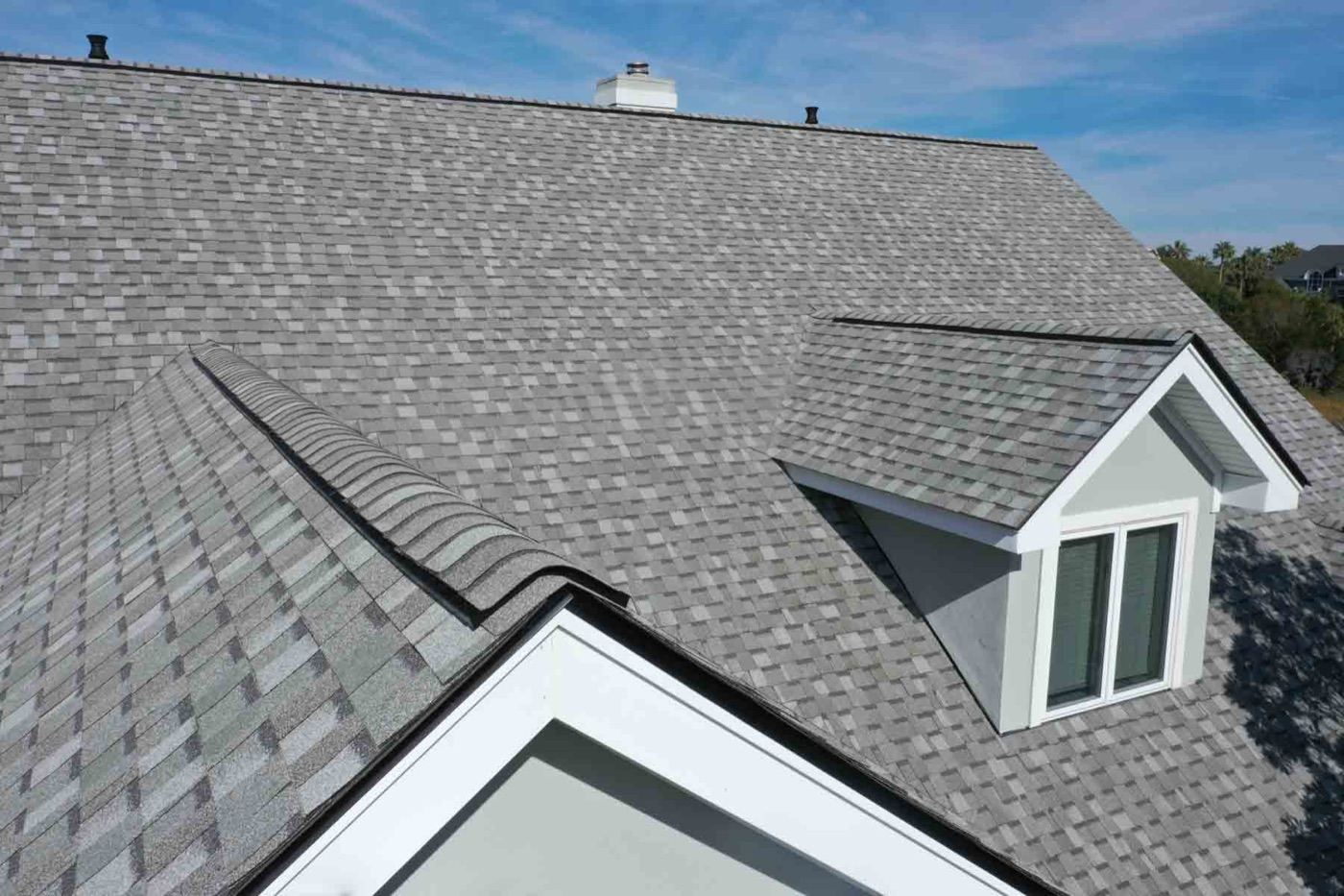 Close-up detail of a new architectural shingle roof with dormer and chimney